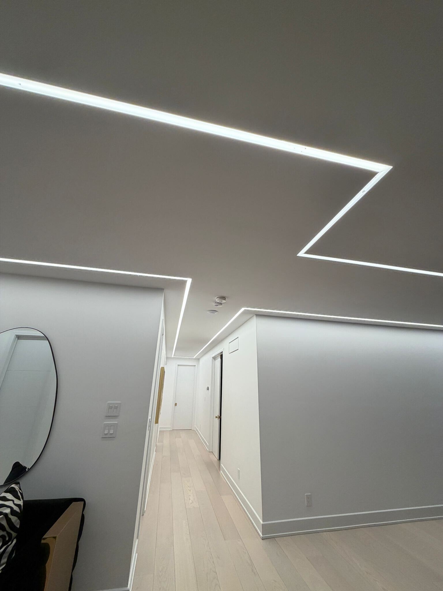 Hallway with angular geometric LED strip patterns running from ceiling to wall