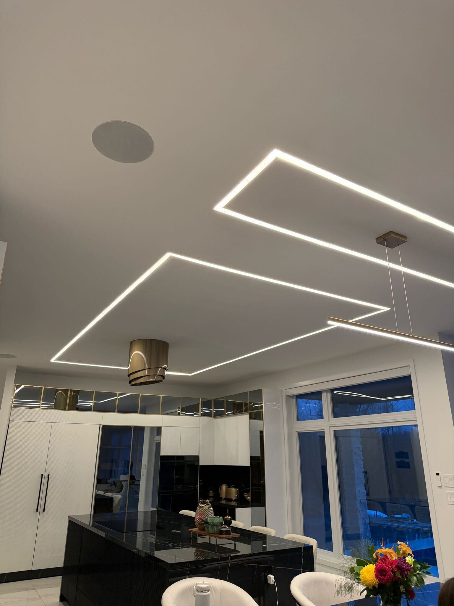 Custom LED strip lighting in a residential kitchen ceiling with overlapping geometric patterns