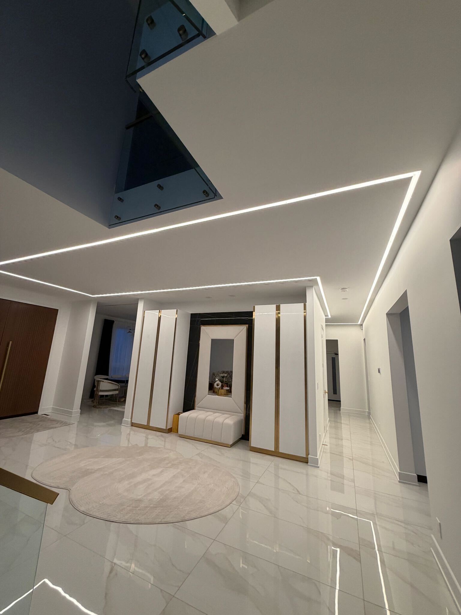 Grand entrance with LED strip lighting in ceiling, marble floors and glass railing